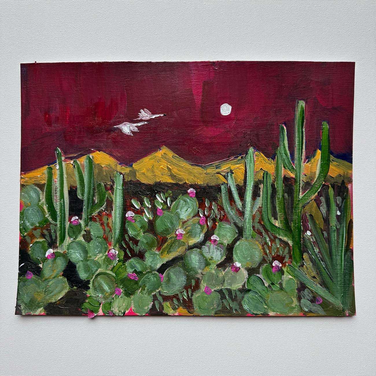 Painting of a desert landscape with cacti, mountains, and a moon.