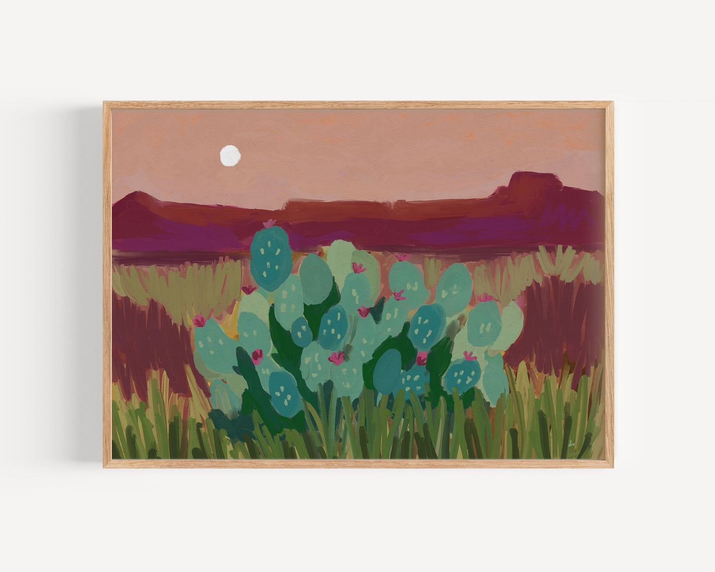 Framed artwork of a desert landscape with cacti and mountains.