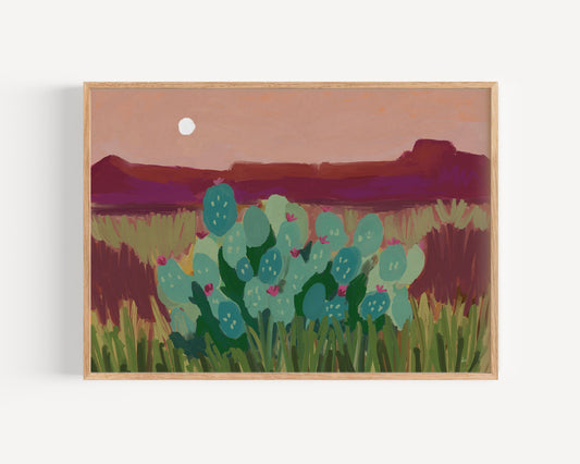 Framed artwork of a desert landscape with cacti and mountains.